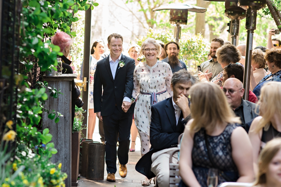 A groom walks down the isle with his mother at his Talula's Garden Wedding.